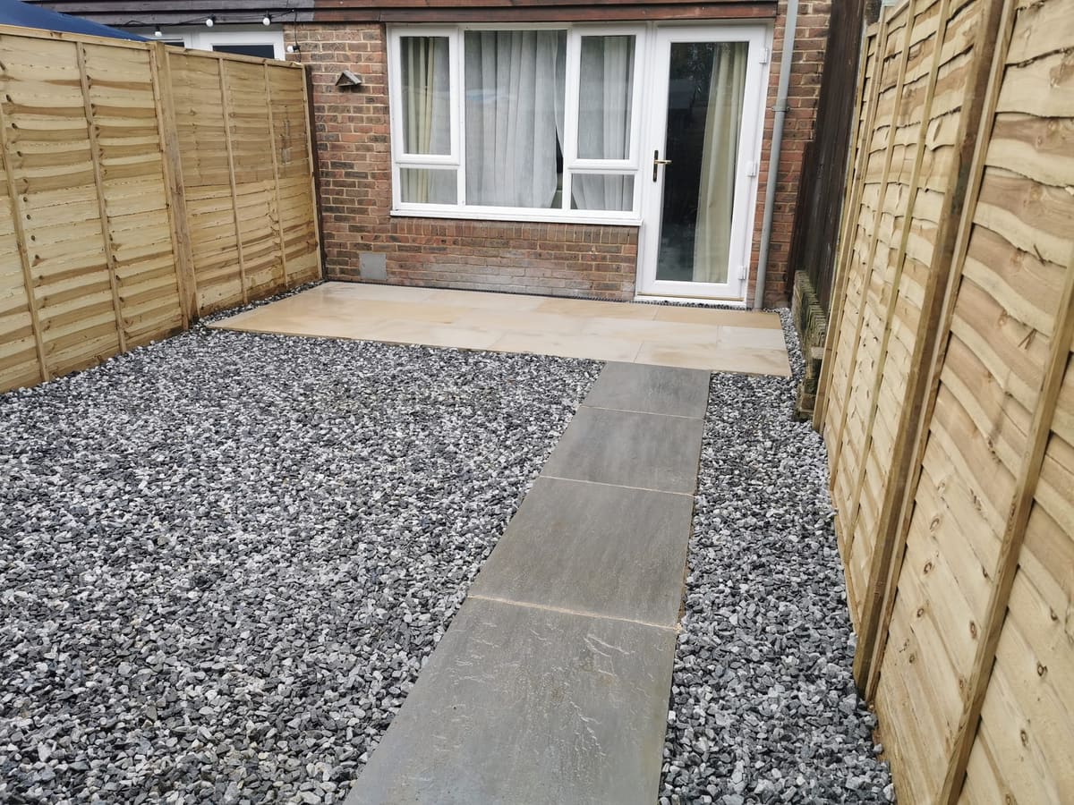 After: Overgrown back yard to a sandstone patio with a slate path and gravel